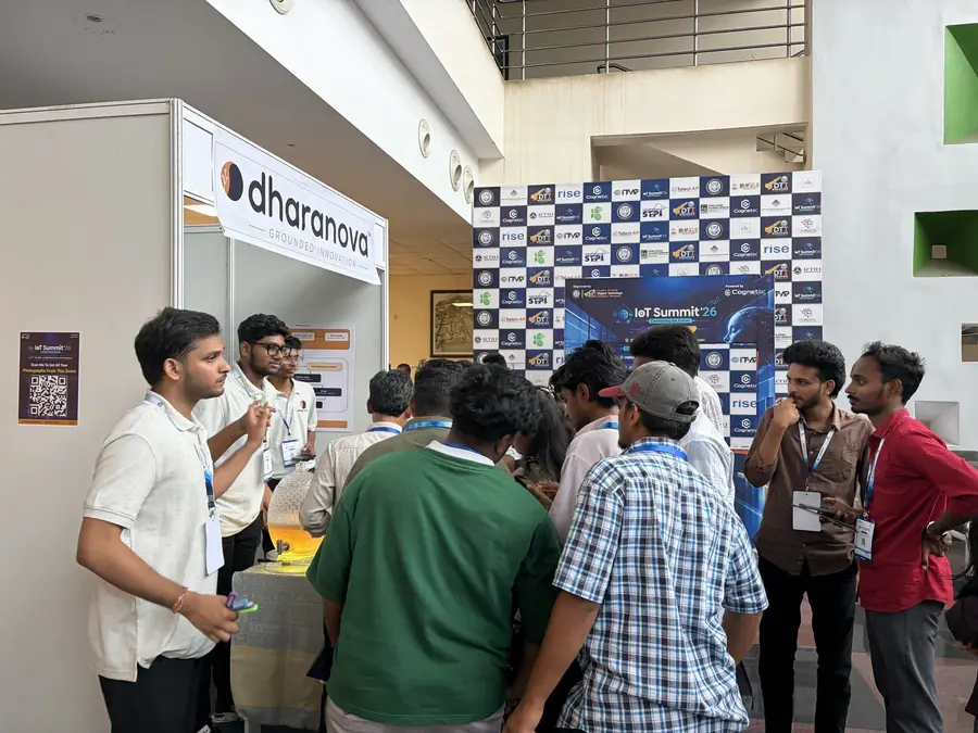 Harsha Vardhan Patri at the Dharanova booth asking visitors to move closer to the centre of the stand, with a crowd gathered around the table.