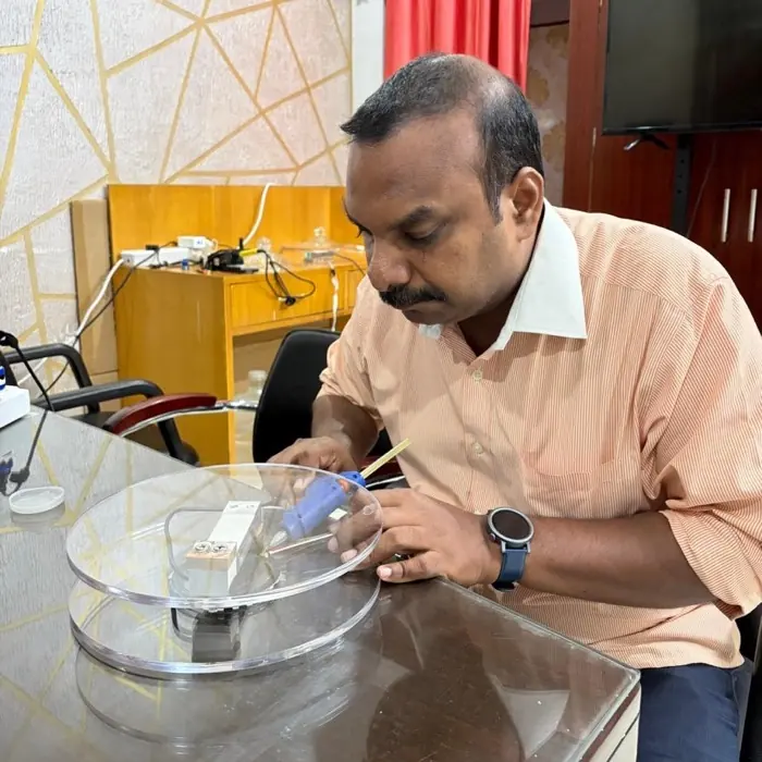 Ravi Kumar Chintalapudi working on the underside of a clear acrylic platform.