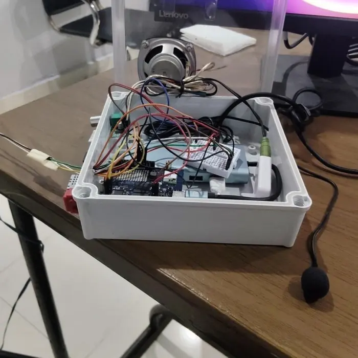 A white junction box with its clear lid raised, showing the board, a speaker and wiring inside.